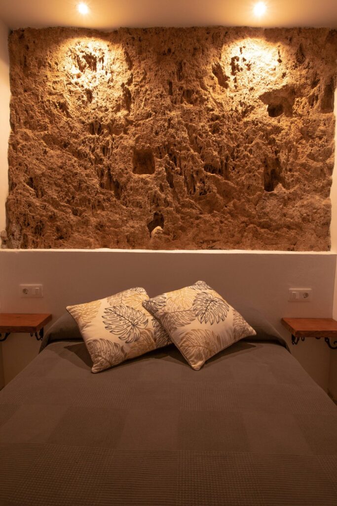Dormitorio principal con pared de piedra natural y cama de 135